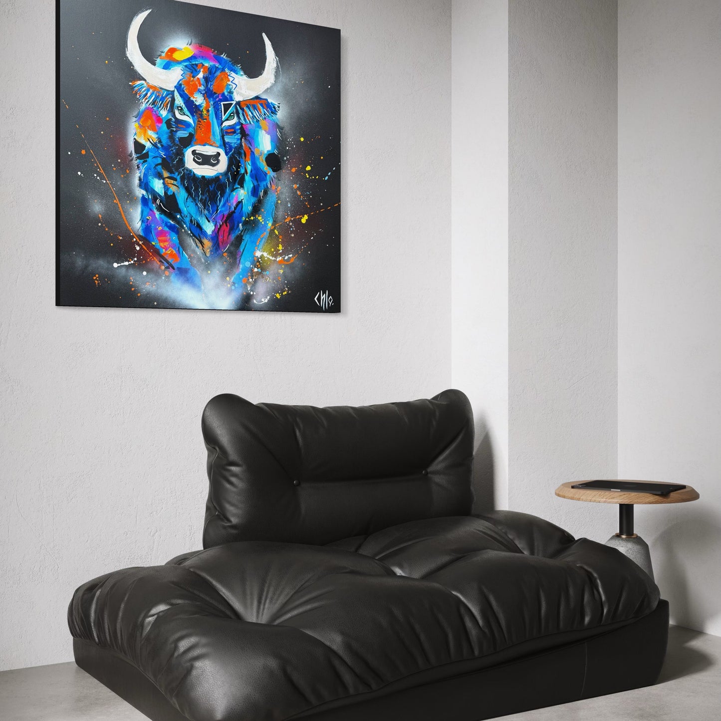 Mise en situation d’un tableau contemporain représentant un taureau coloré et puissant, accroché dans un intérieur moderne et minimaliste, au-dessus d’un fauteuil en cuir noir, soulignant le contraste entre l’œuvre expressive et le décor épuré.